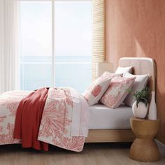 a bed sitting next to a window in a room with white curtains and pink walls