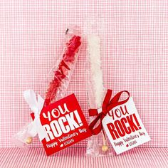 two valentine's day candy sticks wrapped in cellophane and tied with red ribbon