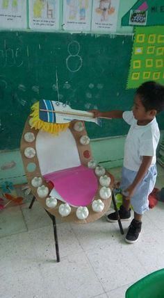 a young boy standing in front of a chair made out of plastic cups and bottles