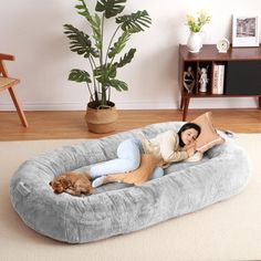 a woman laying on top of a dog bed in the middle of a living room