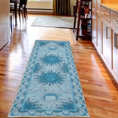 a kitchen area with wooden floors and white cabinets, along with a rug on the floor