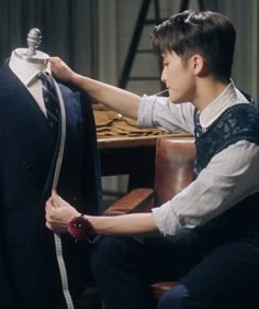 a young man is measuring the size of a suit on a mannequin's dummy