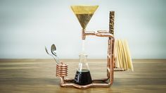 a coffee maker and spoon sitting on top of a wooden table