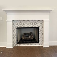 a white fireplace with a black and white tile design on the mantel above it