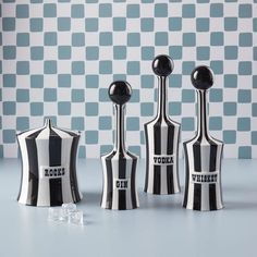 three black and white vases sitting next to each other on a blue counter top