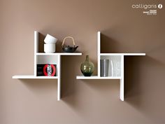 two white shelves with vases and other items on them against a brown painted wall