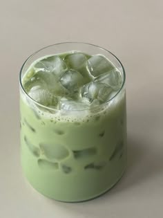 a green drink with ice in it on a table