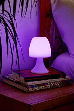 a lamp sitting on top of a stack of books next to a purple light in a bedroom