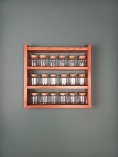 an old wooden shelf with glass jars on it against a gray wall in a room