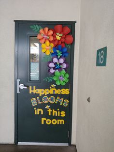 a door decorated with balloons and flowers in front of a classroom sign that says happiness blooms in this room