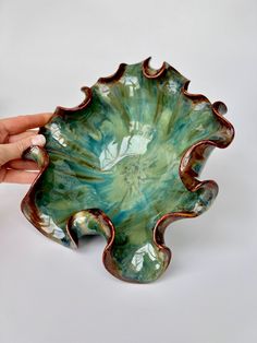 a hand holding a green and brown bowl