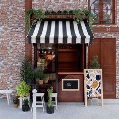 an outdoor cafe with striped awnings and potted plants on the outside wall