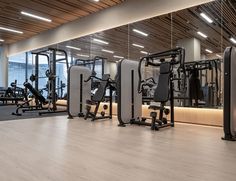 an empty gym with machines and mirrors in the center, along with wooden ceilinging