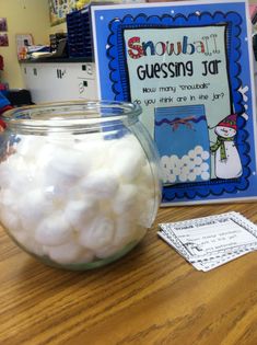 a glass jar filled with white cotton sitting on top of a table next to a book