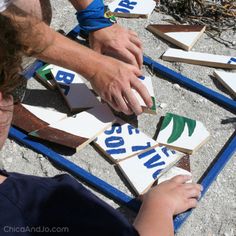 two children are playing with broken tiles on the ground and one child is reaching for them