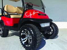 a red golf cart parked in front of a building with a heartbeat on the side