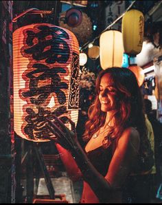 a woman standing in front of a lantern with chinese writing on it