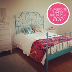 a bedroom with a turquoise metal bed frame and pink pillows on top of the bedspread