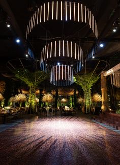 the inside of a building with plants and lights hanging from it's ceiling beams