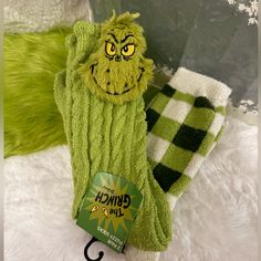 a green mitt with the grin face on it next to a pair of socks