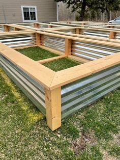 a raised garden bed in the grass with metal slats around it and wood posts