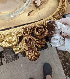 a person holding a piece of cake in front of a gold plate on a table