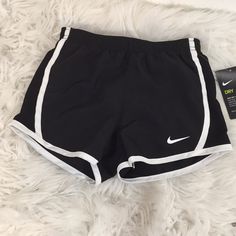 a pair of black and white nike shorts sitting on top of a fluffy white blanket