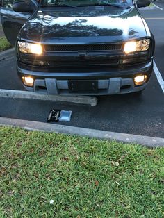 a black truck parked in a parking lot next to a tree and grass covered street