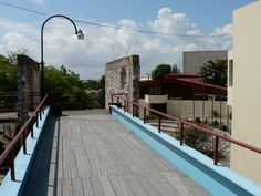 an empty wooden walkway next to a building with a light pole in the middle and trees on both sides