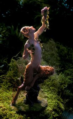 a naked woman with flowers on her head is standing in the middle of some grass