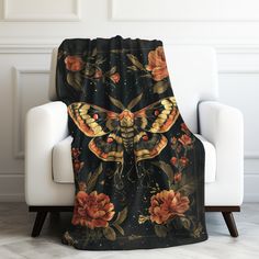 a black and orange butterfly blanket sitting on top of a white chair in front of a wall