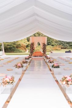 an outdoor wedding setup with white linens and pink flowers on the aisle, along with cookies