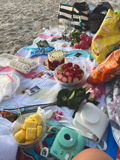 a beach picnic with food and drinks on the sand