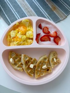 a pink plate topped with waffles and fruit