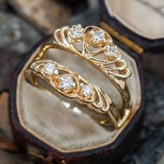 two gold rings with diamonds sitting in a box