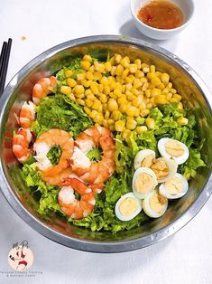 a large salad with shrimp, boiled eggs and corn