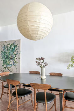 a dining room table with chairs and a vase filled with flowers on top of it