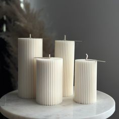 three white candles sitting on top of a marble table