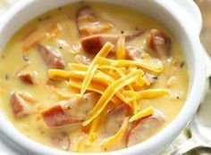 a close up of a bowl of soup with cheese and meat in it on a table