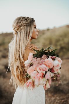 a woman with long blonde hair and braids holding a bouquet of flowers in her hand