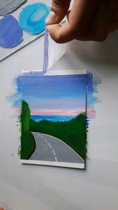 someone is painting a landscape with watercolors