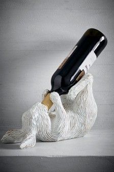 a ceramic animal holding a bottle of wine in it's mouth with its paws