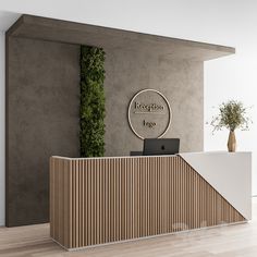 the reception desk has a laptop on it and is next to a wall with a plant