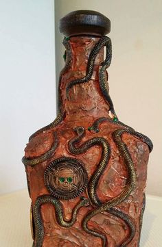 a brown vase with snakes on it sitting on a table