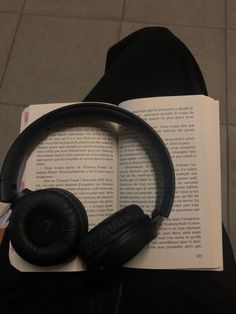 an open book with headphones on it sitting next to a pair of black shoes