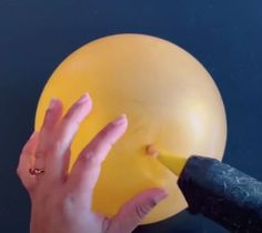 a person's hand reaching for a yellow balloon