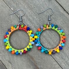 two pairs of colorful beaded hoop earrings sitting on top of a wooden floor next to each other