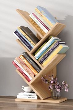 there is a book shelf that has many books on it and a vase with flowers next to it