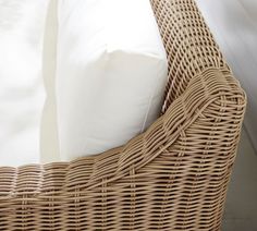 a wicker bed frame with white pillows and sheets in the back ground, close up