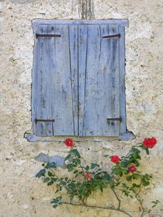 an old window with blue shutters and red flowers